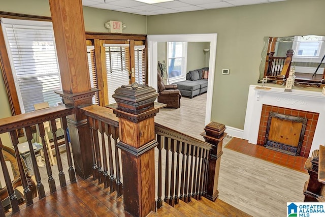 stairway featuring a drop ceiling, a fireplace, and wood-type flooring