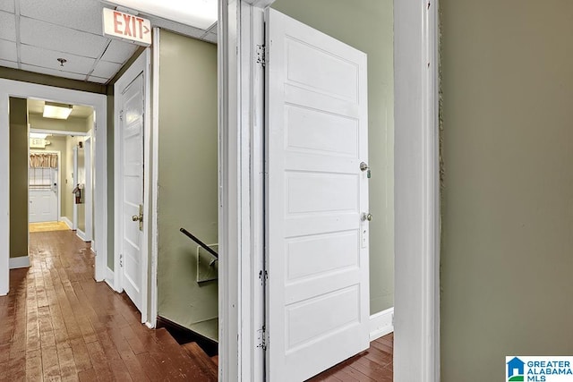 hallway with dark wood-type flooring and a paneled ceiling