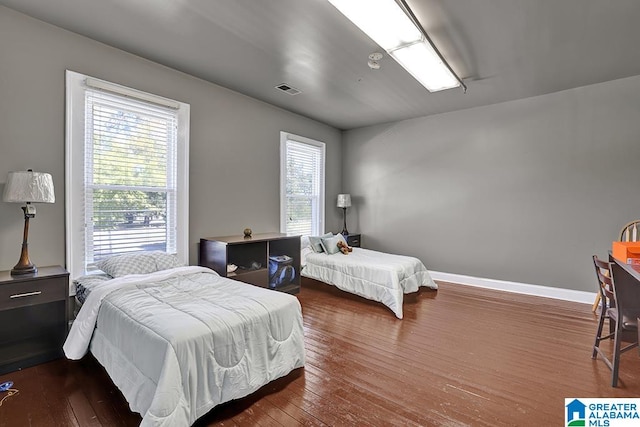 bedroom featuring multiple windows and dark hardwood / wood-style floors