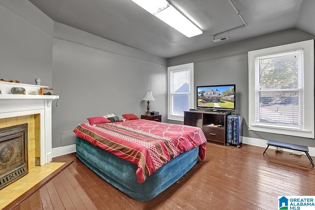 bedroom with hardwood / wood-style floors, a fireplace, and multiple windows