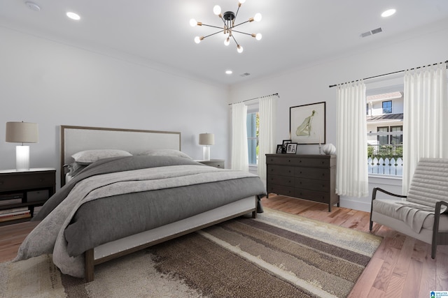 bedroom featuring crown molding, wood-type flooring, and an inviting chandelier