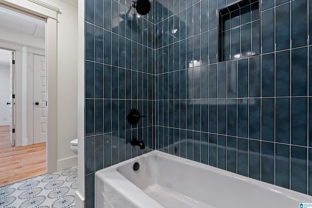 bathroom with wood-type flooring, tiled shower / bath combo, and toilet