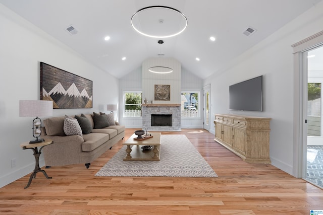 living room featuring light hardwood / wood-style floors, a fireplace, and high vaulted ceiling