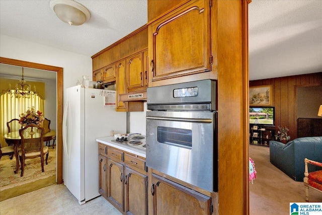 kitchen featuring white appliances, a textured ceiling, hanging light fixtures, light carpet, and an inviting chandelier