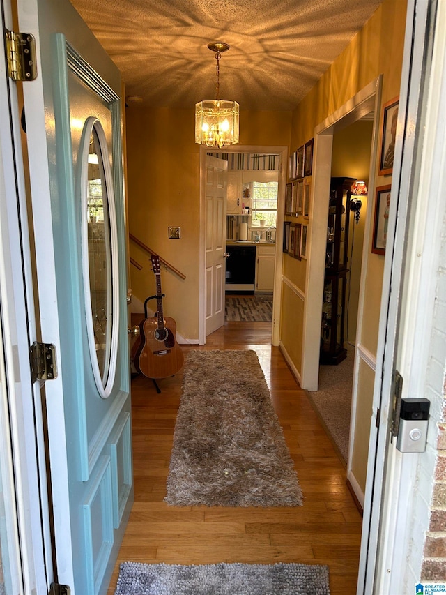 interior space with light hardwood / wood-style floors, a textured ceiling, and a chandelier