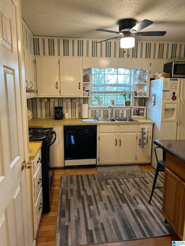 kitchen with black appliances, sink, a textured ceiling, white cabinetry, and dark wood-type flooring