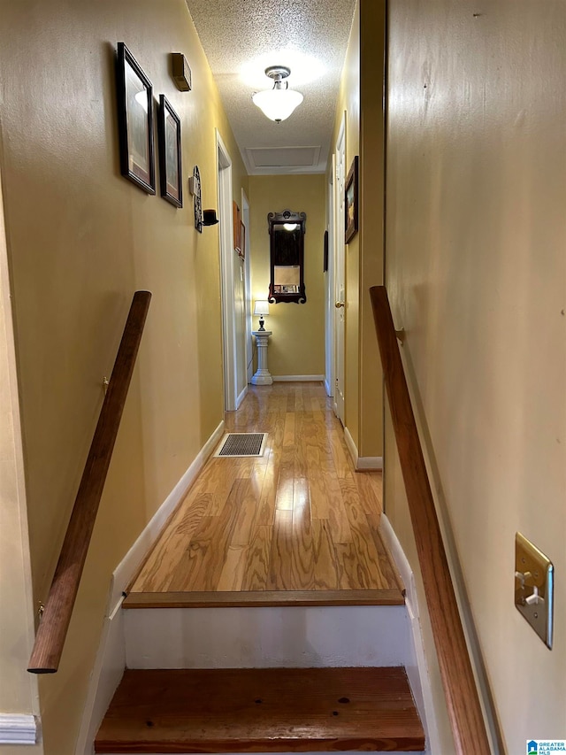 stairs with hardwood / wood-style flooring and a textured ceiling