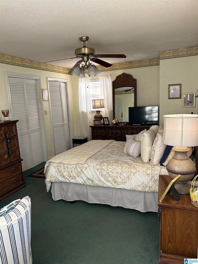 bedroom with a textured ceiling, two closets, carpet flooring, and ceiling fan