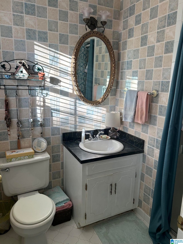 bathroom with toilet, vanity, tile patterned floors, and tile walls