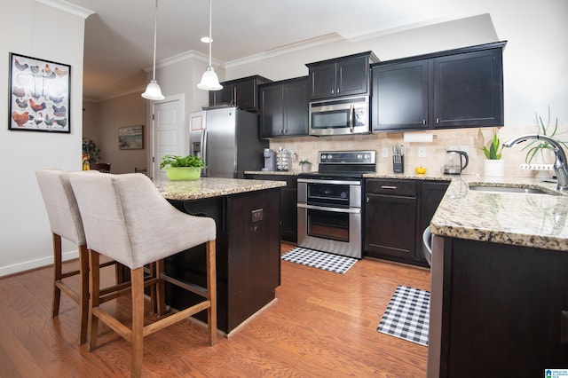 kitchen featuring sink, a center island, stainless steel appliances, and light wood-type flooring