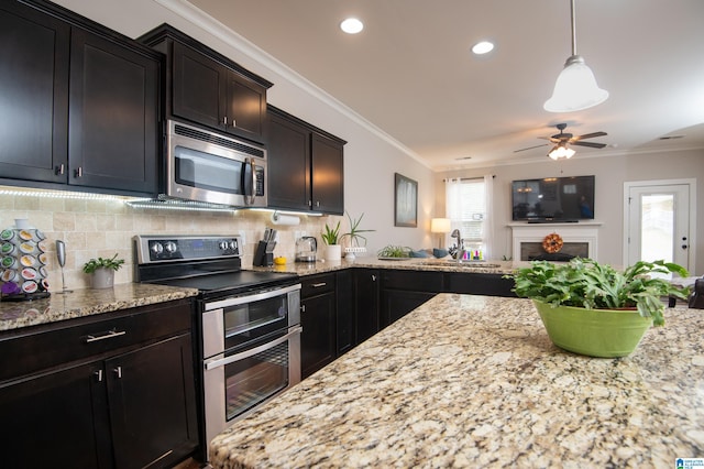 kitchen featuring backsplash, ceiling fan, stainless steel appliances, decorative light fixtures, and ornamental molding