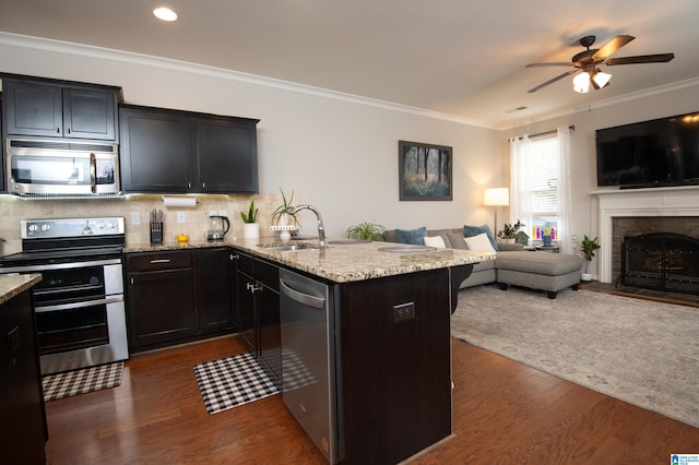 kitchen featuring decorative backsplash, appliances with stainless steel finishes, dark wood-type flooring, crown molding, and light stone counters