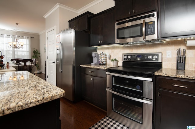 kitchen featuring stainless steel appliances, light stone counters, ornamental molding, an inviting chandelier, and dark hardwood / wood-style floors