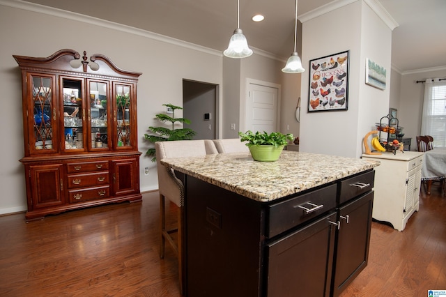 kitchen featuring a breakfast bar area, a kitchen island, dark wood-type flooring, crown molding, and decorative light fixtures