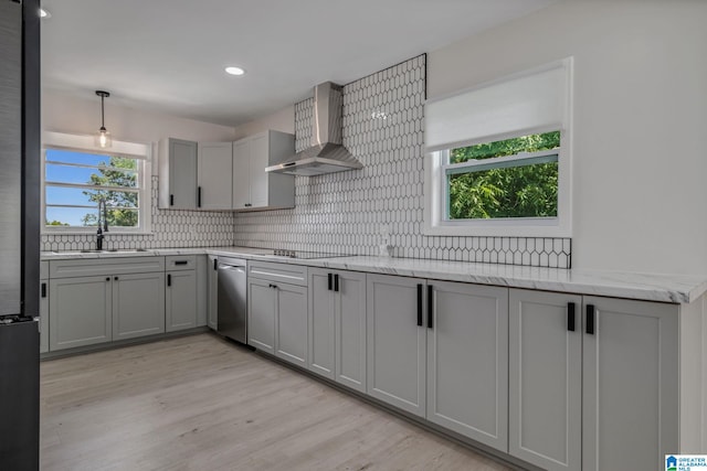 kitchen with wall chimney exhaust hood, light hardwood / wood-style flooring, tasteful backsplash, and plenty of natural light