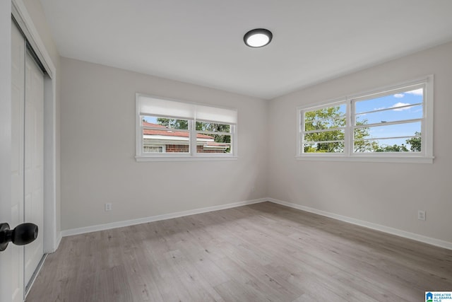 unfurnished bedroom featuring multiple windows, a closet, and light wood-type flooring