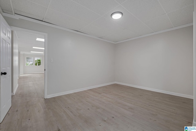 unfurnished room featuring crown molding, light hardwood / wood-style flooring, and a paneled ceiling