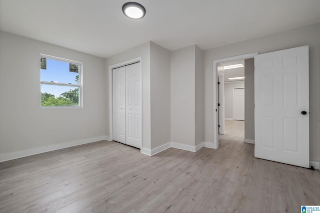 unfurnished bedroom with light hardwood / wood-style flooring and a closet