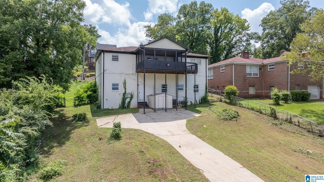 back of property featuring a yard, a sunroom, and a balcony