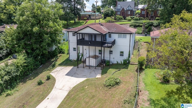 rear view of house with a balcony and a lawn