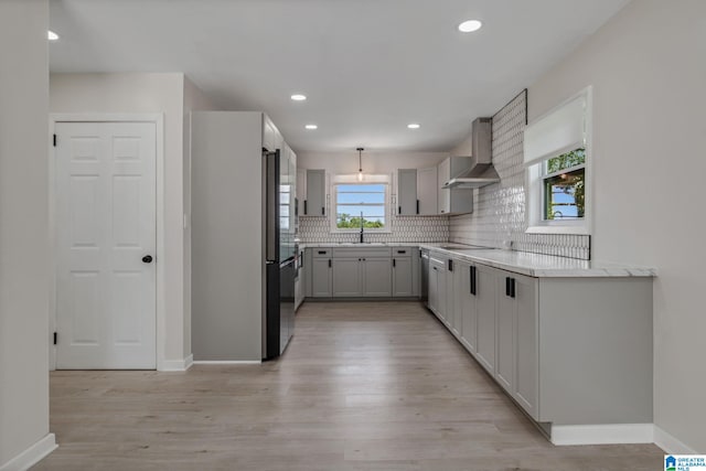 2720 20th Pl, Ensley, Birmingham, AL 35208 - kitchen featuring wall chimney range hood, a sink, decorative backsplash, light wood finished floors, and baseboards