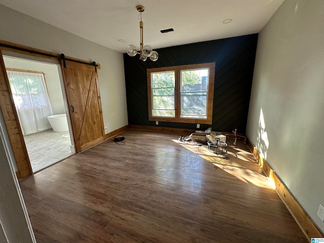 empty room with an inviting chandelier, dark hardwood / wood-style floors, wooden walls, and plenty of natural light