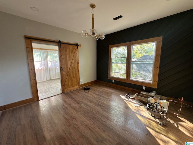 empty room with a barn door, a healthy amount of sunlight, and hardwood / wood-style flooring