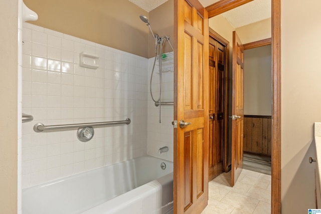 bathroom featuring tile patterned floors, wooden walls, tiled shower / bath combo, vanity, and a textured ceiling