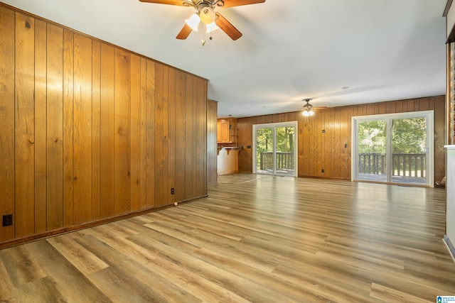 unfurnished living room with light hardwood / wood-style floors and wooden walls