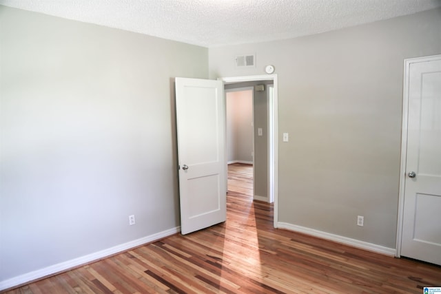 unfurnished bedroom featuring wood-type flooring and a textured ceiling