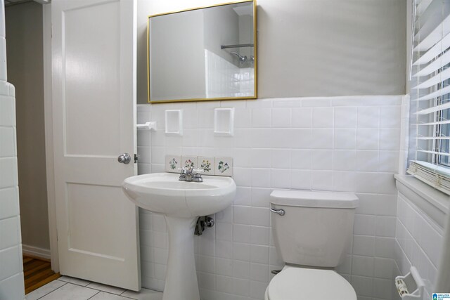 bathroom featuring toilet, tile walls, and tile patterned flooring