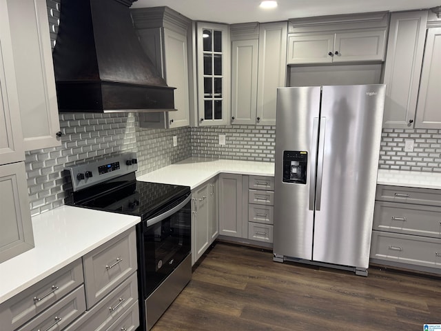 kitchen featuring dark hardwood / wood-style floors, gray cabinets, custom exhaust hood, appliances with stainless steel finishes, and tasteful backsplash