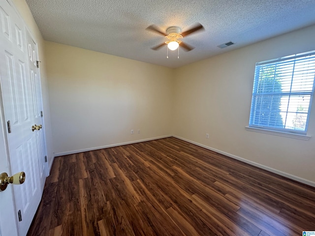 empty room with a textured ceiling, dark hardwood / wood-style floors, and ceiling fan