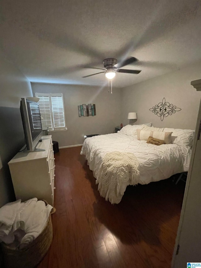 bedroom featuring a textured ceiling, dark wood-type flooring, a ceiling fan, and baseboards