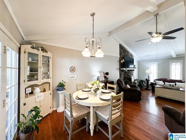 dining space featuring vaulted ceiling with beams, dark wood-style floors, a fireplace, and ceiling fan with notable chandelier