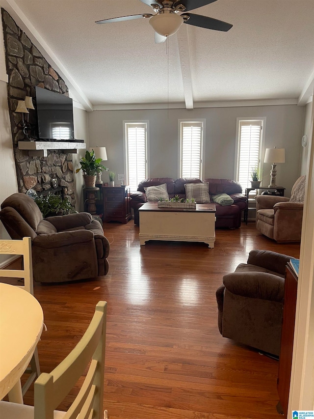 living room with a textured ceiling, wood finished floors, a ceiling fan, and a healthy amount of sunlight