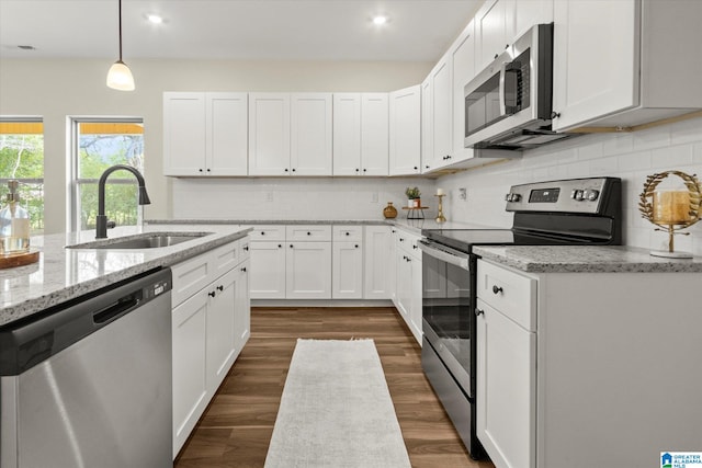 kitchen with appliances with stainless steel finishes, sink, pendant lighting, and white cabinets