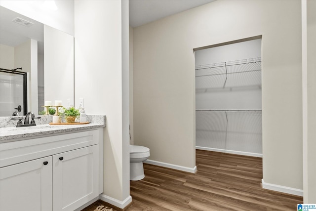 bathroom featuring vanity, hardwood / wood-style flooring, toilet, and walk in shower