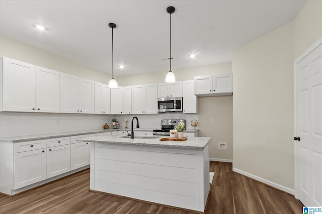 kitchen with appliances with stainless steel finishes, white cabinetry, a kitchen island with sink, pendant lighting, and sink