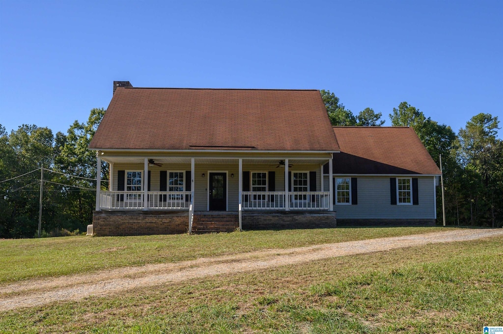 new england style home with ceiling fan, a porch, and a front lawn