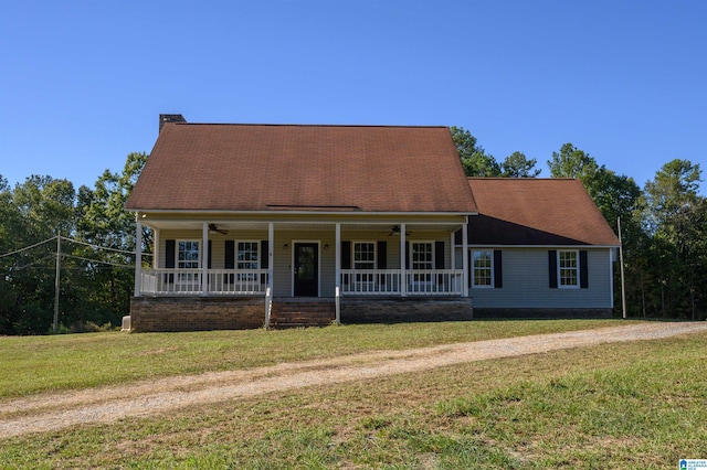 new england style home with ceiling fan, a porch, and a front lawn