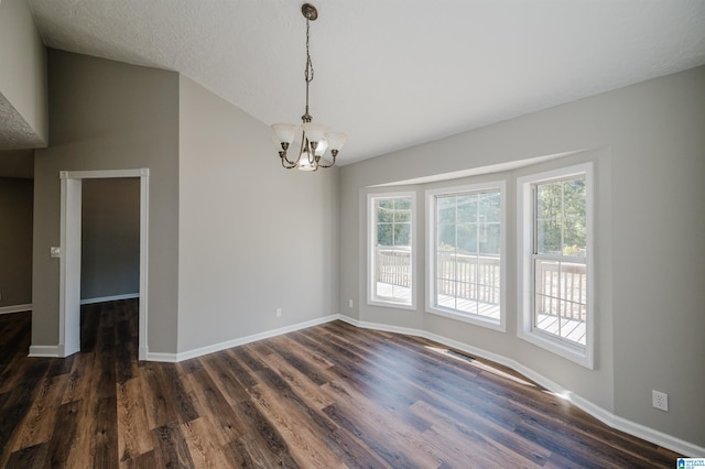 spare room with vaulted ceiling, a textured ceiling, dark hardwood / wood-style flooring, and a chandelier