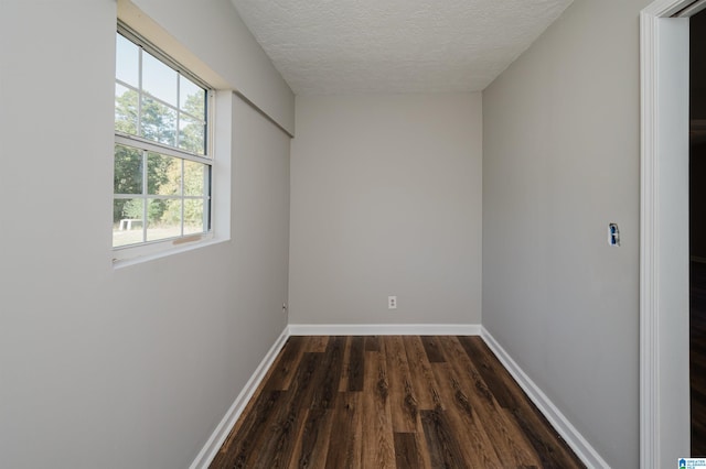 empty room with a textured ceiling and dark hardwood / wood-style flooring