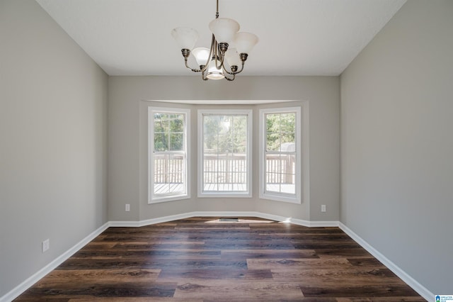 spare room with a notable chandelier and dark hardwood / wood-style flooring