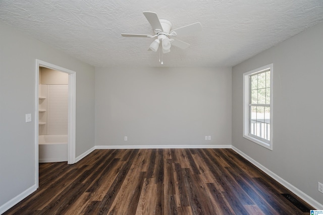 spare room with a textured ceiling, dark wood-type flooring, and ceiling fan