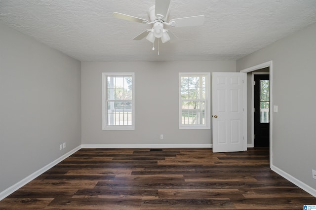 unfurnished room with a healthy amount of sunlight, a textured ceiling, and dark hardwood / wood-style floors