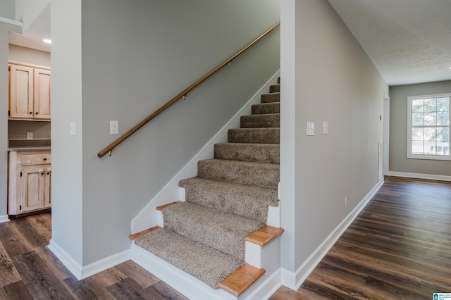 stairway with a textured ceiling and wood-type flooring