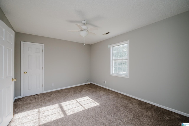 carpeted empty room featuring ceiling fan and a textured ceiling