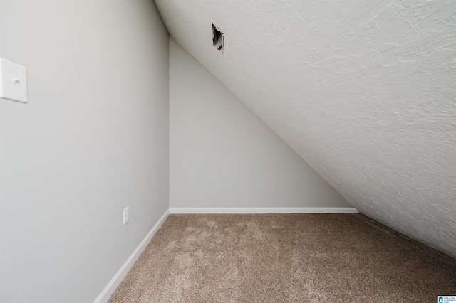 additional living space with lofted ceiling, carpet flooring, and a textured ceiling