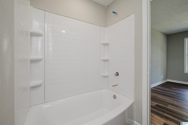 bathroom featuring  shower combination, wood-type flooring, and a textured ceiling